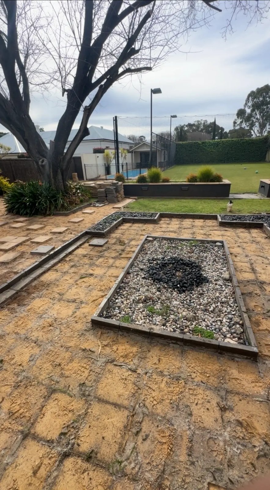 Backyard garden bed area with pavers lifted and stacked ready for pickup