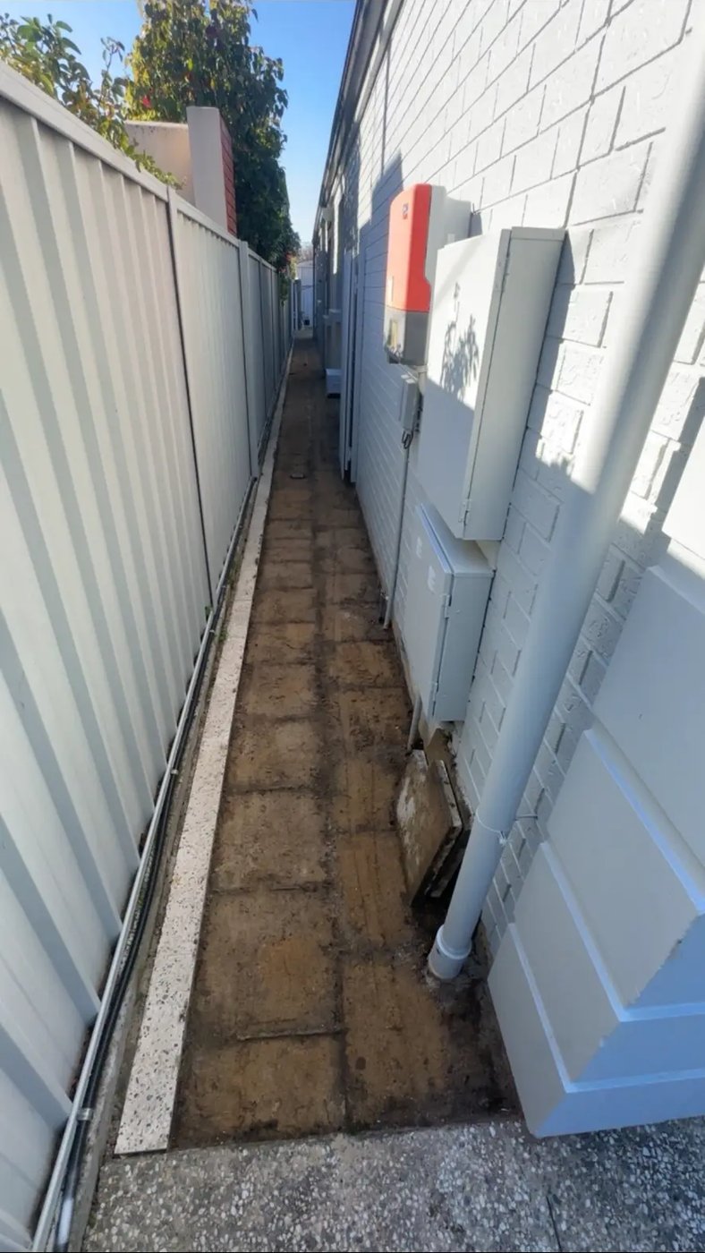 Narrow side path cleared of pavers